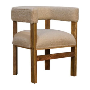 A cosy chair with a cream boucle fabric and a wooden frame and legs