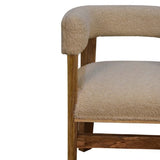 A chair with a thick and dense boucle fabric in a cream hue and a mango wood frame and legs in a light brown hue