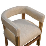 A cream boucle chair with a nubby texture and a wooden frame and legs with a smooth finish