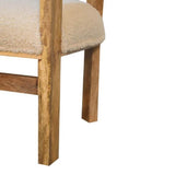 A handwoven boucle chair in a light beige colour with a mango wood structure