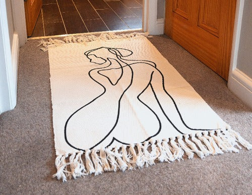 Pair of white rugs with female silhouette designs, featuring two distinct poses, made from natural cotton